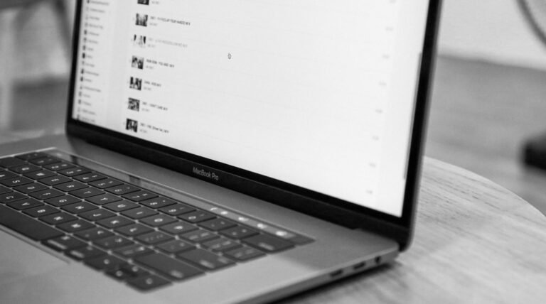 Black and white photo of a MacBook Pro on a round wooden table.